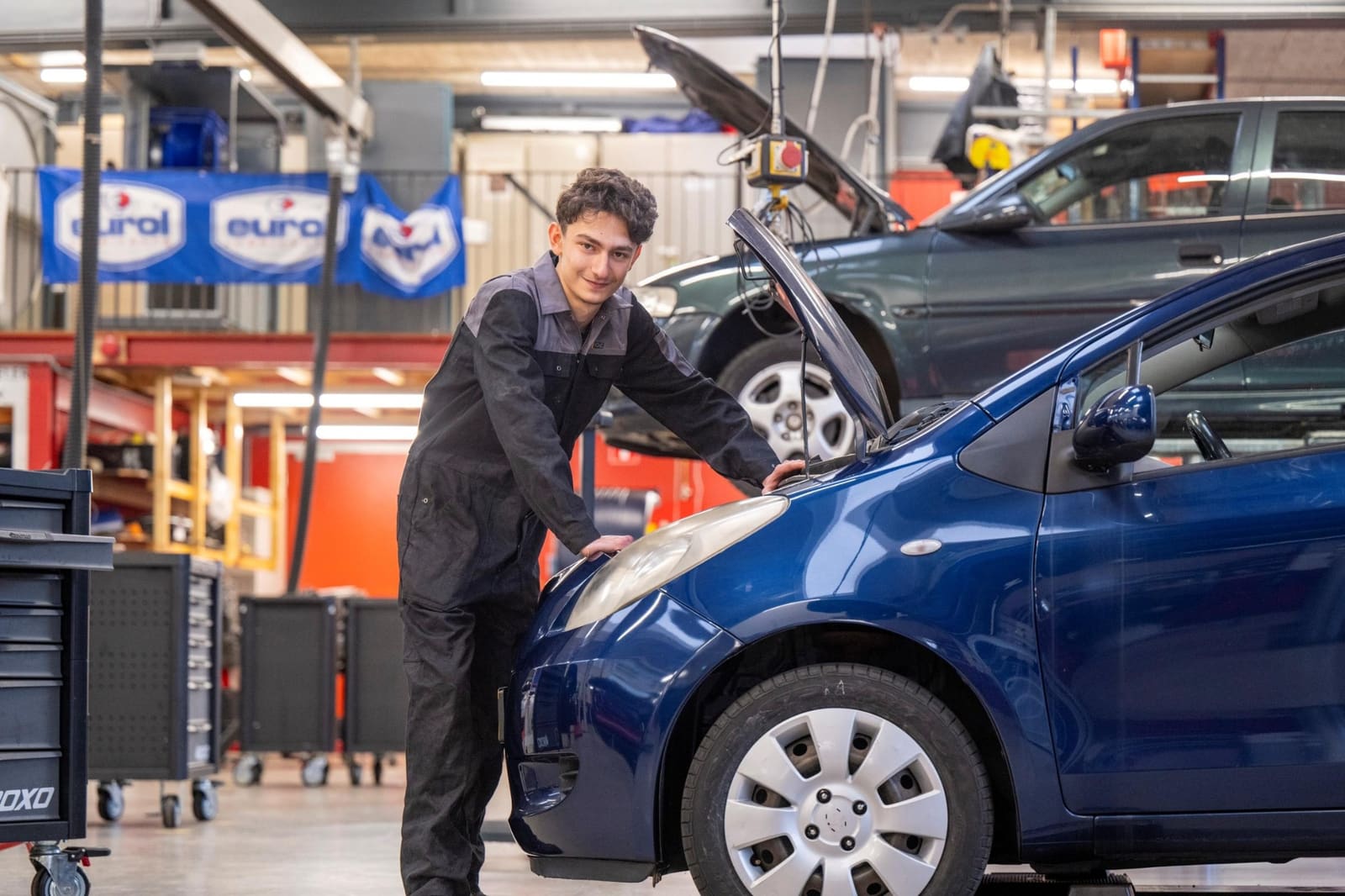 Young person working on a car in a motor-vehicle workshop